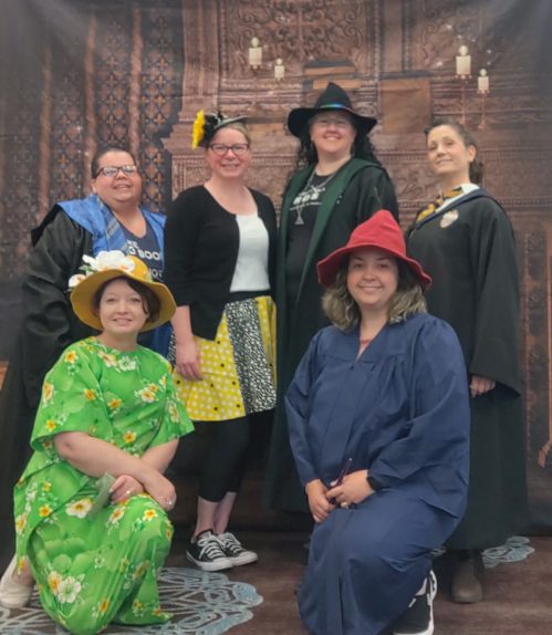 a group of witches in front of a fireplace backdrop